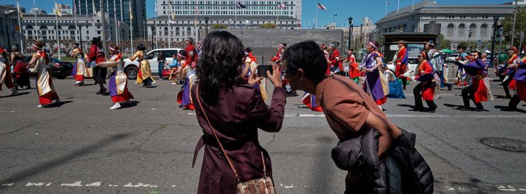 Spectators looking at the back of a camera while photographing a parade