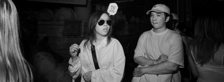 Black and white infrared photograph of a person with a speech bubble sign over their head saying 