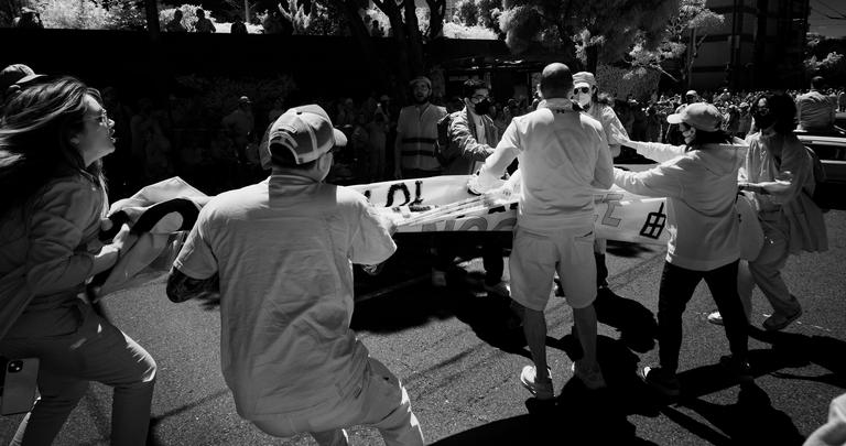 Black and white infrared photograph of a tug of war over a protest banner