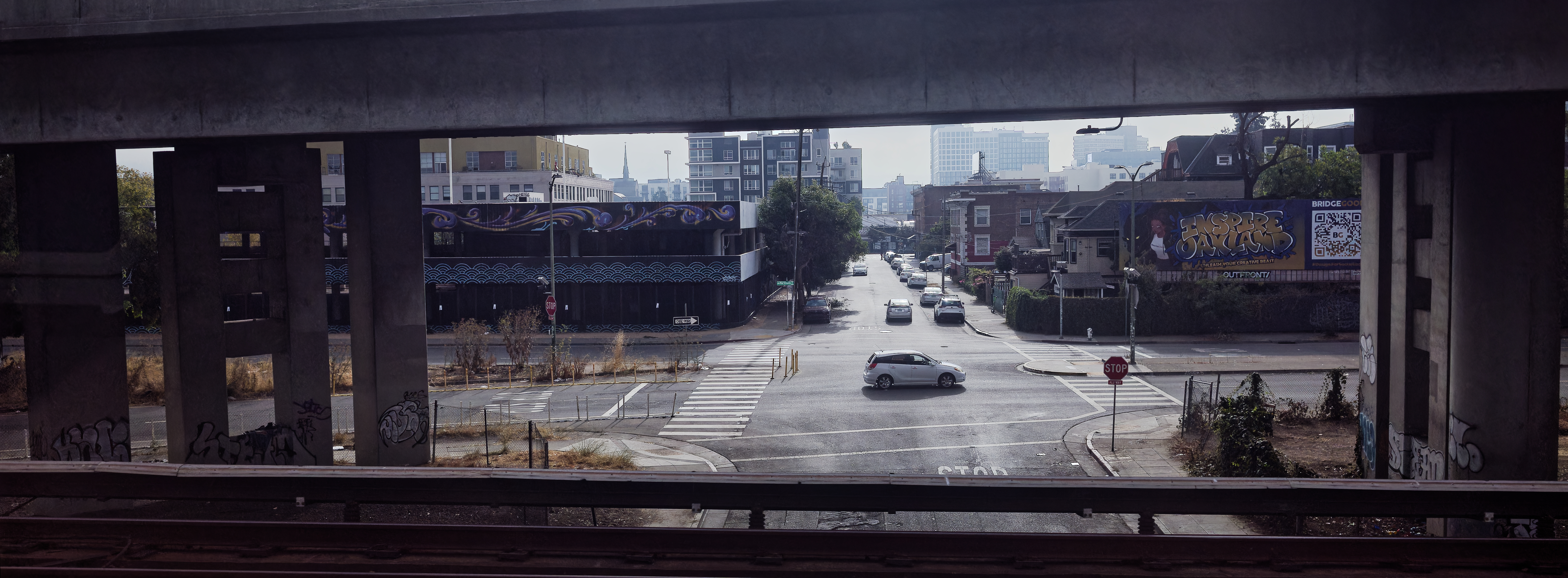 Panoramic crop photo from train window beneath freeway overpass on an intersection on a foggy day