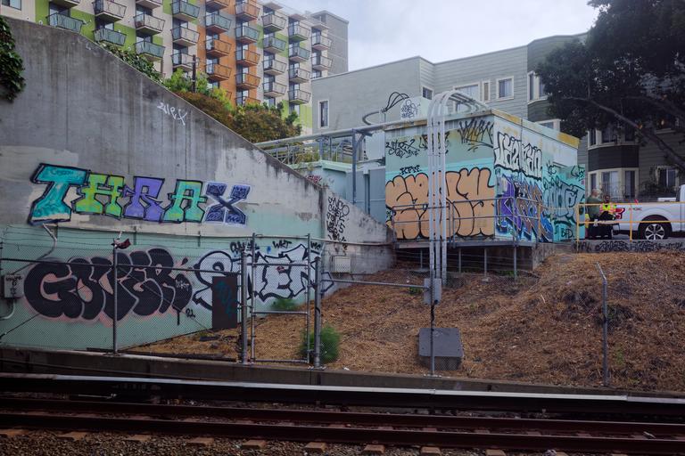 Photograph of BART infrastructure which has been graffitid in lovely pastel shades, seen from train emerging from tunnel